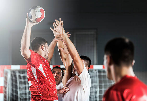 Joueur de handball essayant de marquer pendant que d'autres joueurs tentent de l'en empêcher